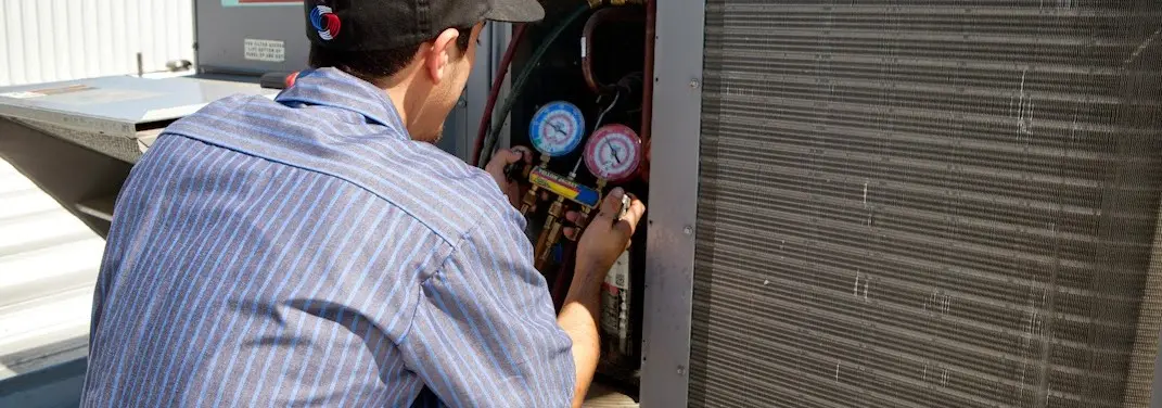 HVAC technician servicing a condenser unit in Bellmead